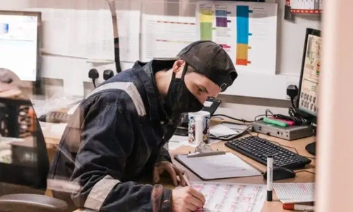 A man wearing protective clothing writing on a piece of paper
